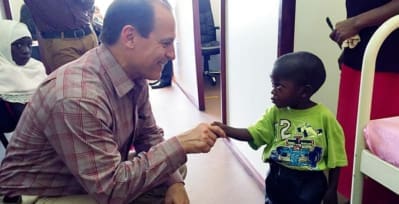 Russell E. Ware M.D., Ph.D., shaking hands with a young sickle cell patient in Africa.