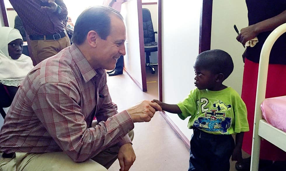 Russell E. Ware M.D., Ph.D., shaking hands with a young sickle cell patient in Africa.