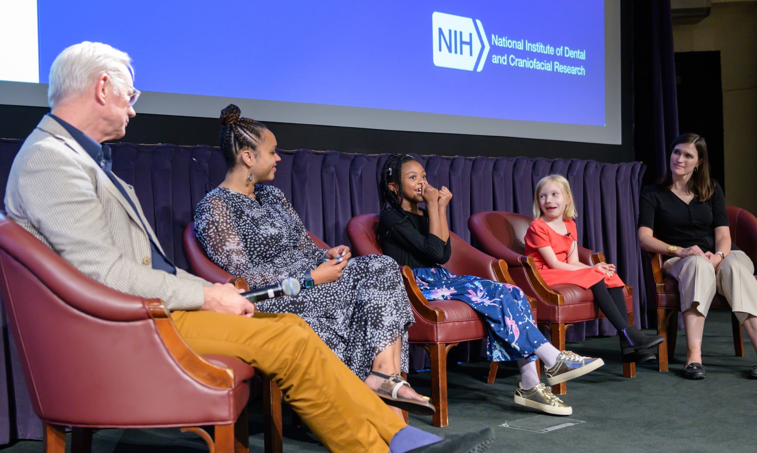 Dr. Michael Collins (far left) and Dr. Alison Boyce (far right) speaking with patient community members about their experiences with FD/MAS.